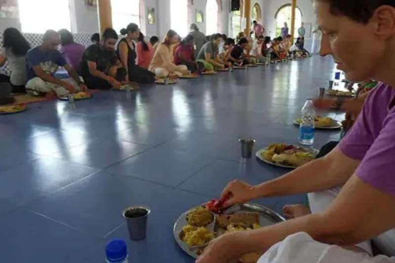 An image of Ashtangis sitting down for a meal together to depict the community aspect of the lifestyle.